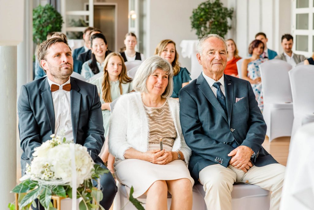 Gäste sitzen in festlichem Veranstaltungssaal zusammen.