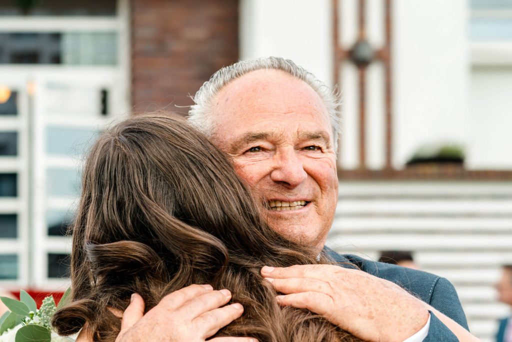 Älterer Mann umarmt eine junge Frau glücklich.