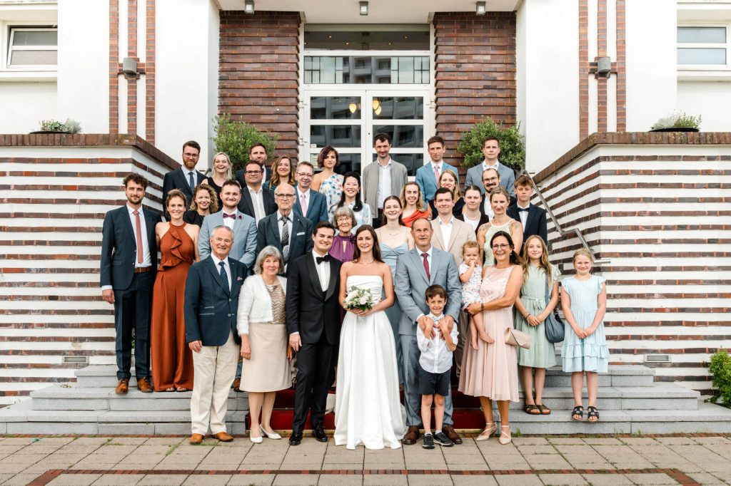 Gruppe posiert für ein Hochzeitsfoto vor Gebäude