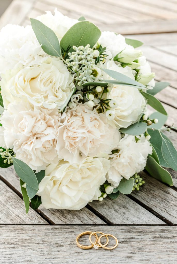 Weiße Hochzeitsblumenstrauß und goldene Trauringe zusammen