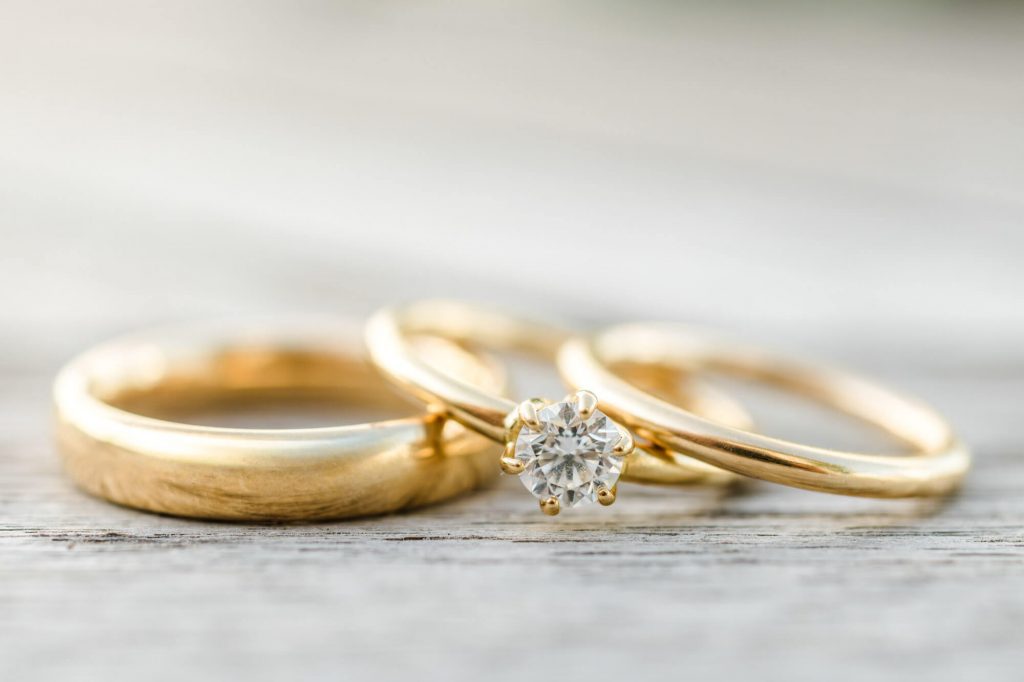 Drei goldene Ringe mit Diamant auf Holztisch