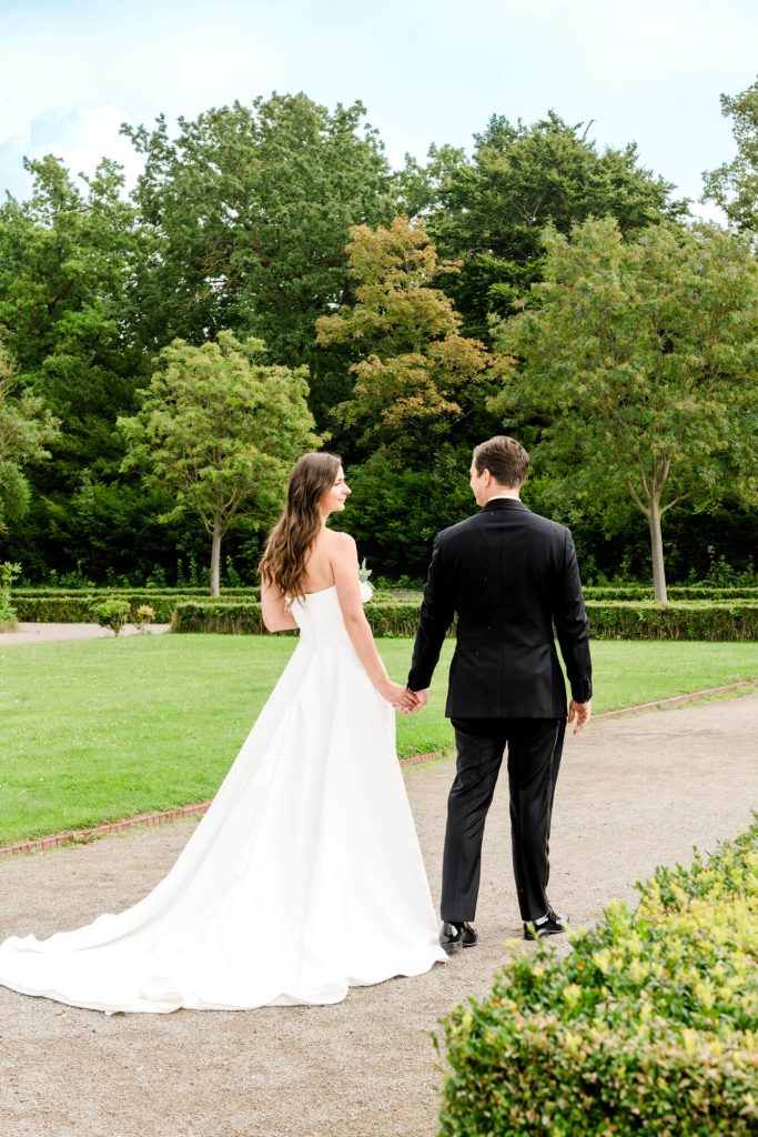 Brautpaar spaziert im Garten am Hochzeitstag