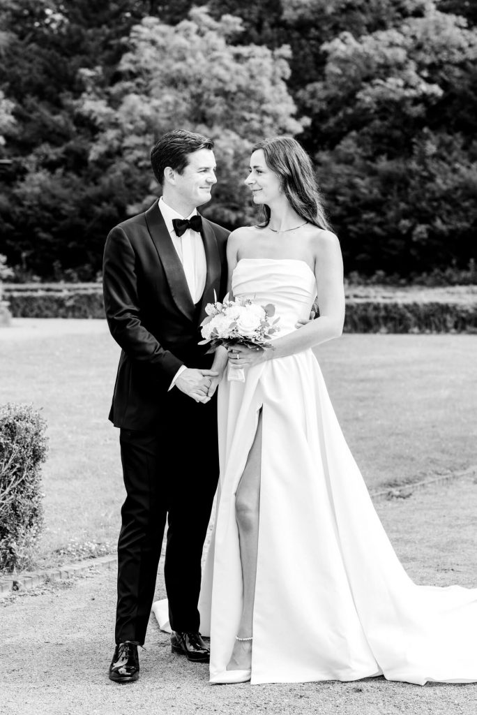 Elegantes Hochzeitspaar posiert im Garten zusammen.