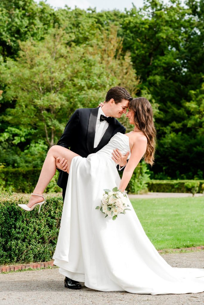 Elegantes Hochzeitspaar im Garten posiert romantisch