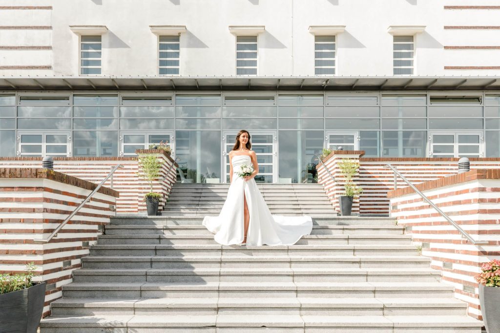 Braut steht auf Treppe vor modernem Gebäude