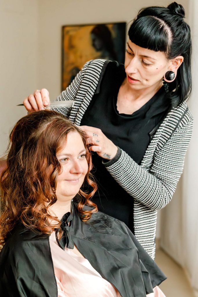Friseurin stylt Haare einer Kundin im Salon